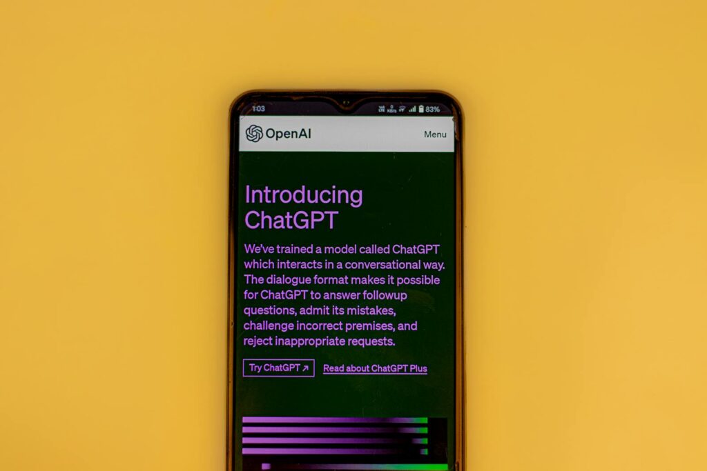 Mobile phone displaying the ChatGPT introduction screen with OpenAI branding on a yellow background.