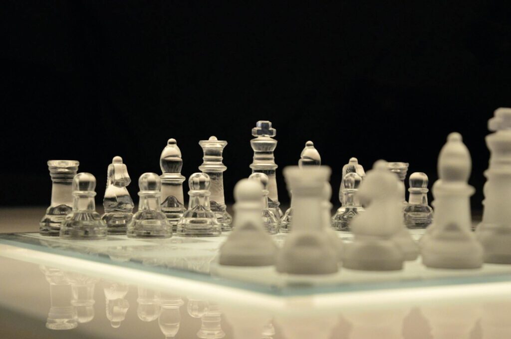 Close-up of a glass chess set with a reflection, emphasizing strategy and elegance.
